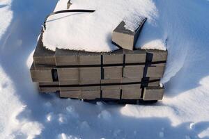 A layer of snow blankets a pile of bricks in an urban design setting photo