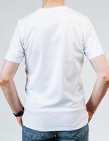 Man in white tshirt and blue jeans showing back with watch on wrist photo