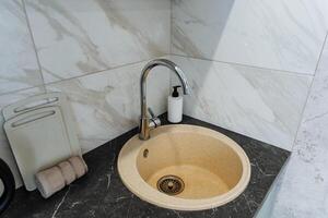 The kitchen sink is wellequipped with a faucet and a conveniently placed soap dispenser on the countertop, making them easily accessible for food prep and cleaning tasks photo