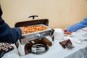 An individual is thoughtfully selecting a tray filled with a wide array of delicious food from an extensive buffet, showcasing diverse cuisines and flavors that everyone can enjoy photo