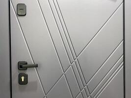 This image showcases a closeup view of a gray door featuring a sleek black handle, emphasizing the doors design and texture for a better visual appreciation and detail photo