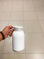 Image shows a person in kitchen with white pitcher, focusing on Gesture, Gas, Kitchen appliance and Milk, with keywords Drinkware, Flooring, Plant milk, Hemp milk, Cylinder photo