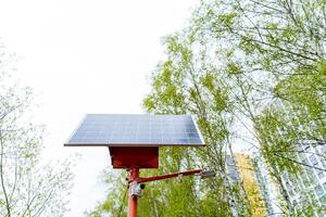 A solar panel rests on a crimson pole under the vast sky photo