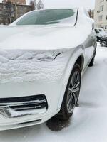 A white car is currently covered in a layer of snow as it sits on a snowy street, surrounded by the winter wonderland that nature has created during this freezing season photo