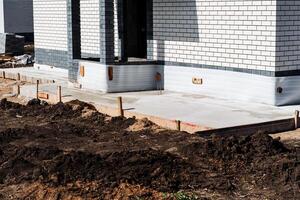 A modern house construction site with brick walls and fresh concrete foundation. The exterior of the unfinished house showcases the use of modern architecture and construction materials photo