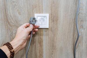 A person is carefully plugging an electrical plug into a wall outlet to ensure a secure connection, allowing essential appliances to function safely and effectively all day photo
