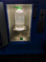A bottle that is completely filled with refreshing water is currently resting on the inside of a vending machine, eagerly waiting to be purchased by a thirsty customer in need of a drink photo