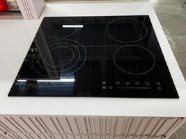 A sleek black stove top oven is elegantly positioned on a pristine white countertop, adding a modern touch to the overall kitchen design and functionality in this home environment photo