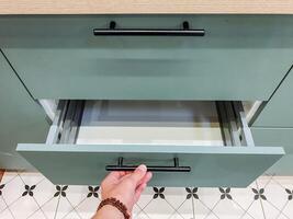 In a wellequipped kitchen, a person meticulously opens a drawer, revealing a diverse array of utensils and essential items crucial for both cooking and food preparation tasks photo