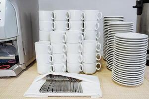 There is a tall stack consisting of various coffee cups and plates placed neatly on a counter, showcasing a blend of colors and sizes, adding a lively essence to the workspace photo