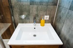 A bathroom sink that has a soap dispenser conveniently placed right on top of it, which significantly enhances both the overall functionality and cleanliness of the bathroom space photo