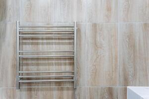 A stylish and sleek stainless steel towel rack elegantly hangs on a beautifully tiled wall in a welldesigned modern bathroom, adding both functionality and aesthetics to the overall space photo