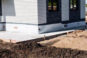 Detailed closeup of the foundation and wall of a newly constructed modern brick house with black and white tiles, showcasing the solid base and modern design of the building photo