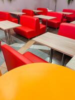 A row of red benches and tables in a restaurant photo