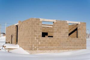 A brick building with a snowy facade is rising against the sky on a snowy slope photo