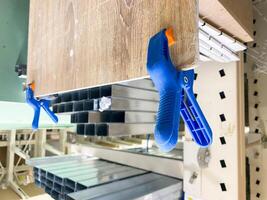 In the busy store, a blue clamp secures a large timber piece, enabling customers to admire and browse a wide range of construction products, enhancing their shopping experience photo