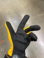 A person wears distinctive black gloves with bright yellow accents, designed for optimal protection and functionality, enhancing safety and style in professional and casual activities photo