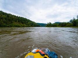 A bright yellow bag is gracefully floating atop the shimmering and reflective surface of a serene river, beautifully surrounded by the vibrant and stunning beauty of natures elements photo