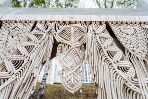 Close up of a textile art macrame wall against a white building facade photo