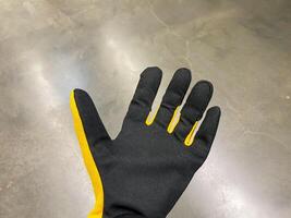 This image presents a closeup view of a Black and Yellow Work Glove resting on a rough and textured concrete surface, showcasing its unique design and intricate details photo