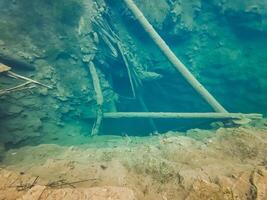 A ladder submerged in water near rocks offers a special underwater perspective, combining leisure, art, and nature in the landscape, highlighting the peacefulness of the setting photo