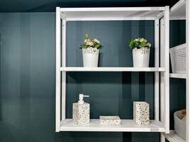 In the bathroom, there is a beautifully arranged white shelf adorned with an array of vibrant flowers and stylish soap dispensers placed neatly on it, adding to the decor photo