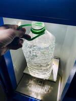 A person is firmly holding a bottle of water that features a distinct green handle, showcasing the container designed for carrying and consuming water conveniently and efficiently photo