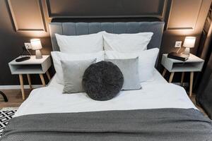 In a cozy bedroom, there is a beautifully made bed adorned with crisp white sheets and fluffy pillows, accompanied by two elegant nightstands on either side for added functionality photo