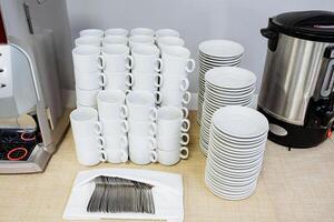 A beautifully arranged table features an organized stack of charming coffee cups and plates, creating an inviting ambiance for enjoying a warm beverage or meal with friends photo