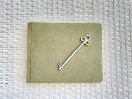 A vintage key on a notebook, creating an elegant composition against a woven backdrop in a still life setting photo
