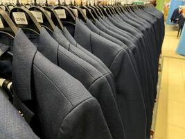 In a beautifully designed store display, elegant blue suits hang on neatly arranged racks, showcasing the latest collection for customers to browse and enjoy their shopping experience photo