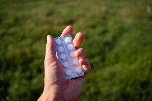 A person is currently holding a blister pack of pills tightly in their hand, showcasing the distinctiveness of the packaging and the contents that are designed for medical use photo