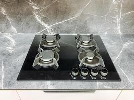 The contemporary kitchen features a gas stove with four reliable burners on a striking marble countertop, enhancing sophistication and making it ideal for culinary creativity photo