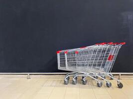 The image shows empty shopping carts against a black wall, presenting a minimalist view that effectively captures the essence of a retail environment photo
