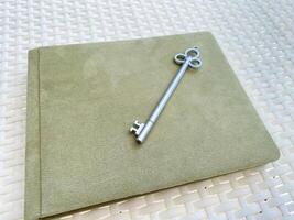 On the green envelope lies a gleaming silver key. The description features keywords like rectangle, beige, font, fashion accessory, gadget, metal, paper product, pattern, paper, and circle photo