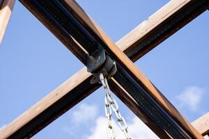 A sturdy chain is elegantly hanging down from the ceiling of a beautifully crafted wooden structure, adding both functionality and aesthetic appeal to the overall architecture photo
