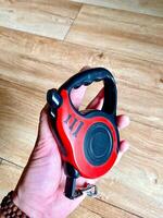 A Compact Red Retractable Dog Leash is being held in hand, making it convenient and easy for walking your beloved pet with comfort photo