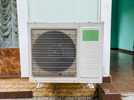 A white air conditioning unit is securely mounted on the exterior of a tall building, providing essential cooling and effective ventilation for the comfort of the occupants inside the rooms photo