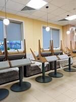 In a spacious room, there exists a long row of tables, accompanied by chairs that are neatly arranged, which collectively contribute to the overall design and ambiance of the interior space photo