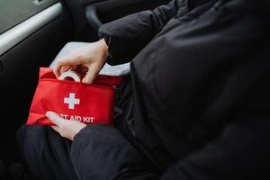 Inside a vehicle, a person is seated comfortably and securely, equipped with a first aid kit, all set to provide immediate medical assistance to anyone in need during an emergency situation photo