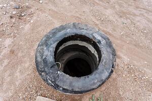 An abandoned circular well on muddy ground represents a forgotten ancient construction in a desolate landscape photo