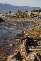 A River Runs Through A Small Village With Mountains In The Background photo