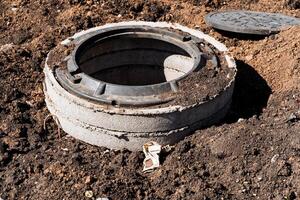 Construction site with exposed manhole, digging earth for concrete structure installation. Prep work for infrastructure development and utility installation in urban environment photo