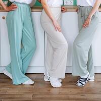 There are three women who are standing together in close proximity to one another, each of them wearing stylish wideleg pants that add a trendy touch to their appearance photo