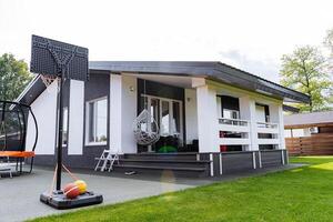 In front of a house, there is a basketball hoop installed, which adds a recreational element to the property, inviting fun and activity for those living there as well as visitors photo