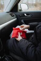 A person is seated comfortably inside a vehicle, holding a comprehensive first aid kit, which clearly indicates their readiness for any unexpected emergencies or injuries that might arise photo