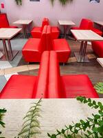 There is a vibrant restaurant that is beautifully decorated with inviting red chairs and tables, creating a warm and lively atmosphere for patrons to enjoy their meals and social events photo