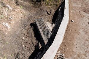 Drain being installed on road side to manage water runoff, improve landscape photo