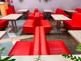 The restaurant features an inviting atmosphere, adorned with vibrant red chairs and tables that enhance its aesthetic appeal, creating a lively ambiance for guests to enjoy their meals photo
