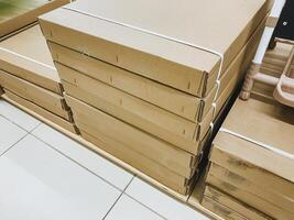 There is a stack of cardboard boxes that are positioned neatly on top of one another resting on a shelf. These boxes are organized and are made of durable cardboard material photo